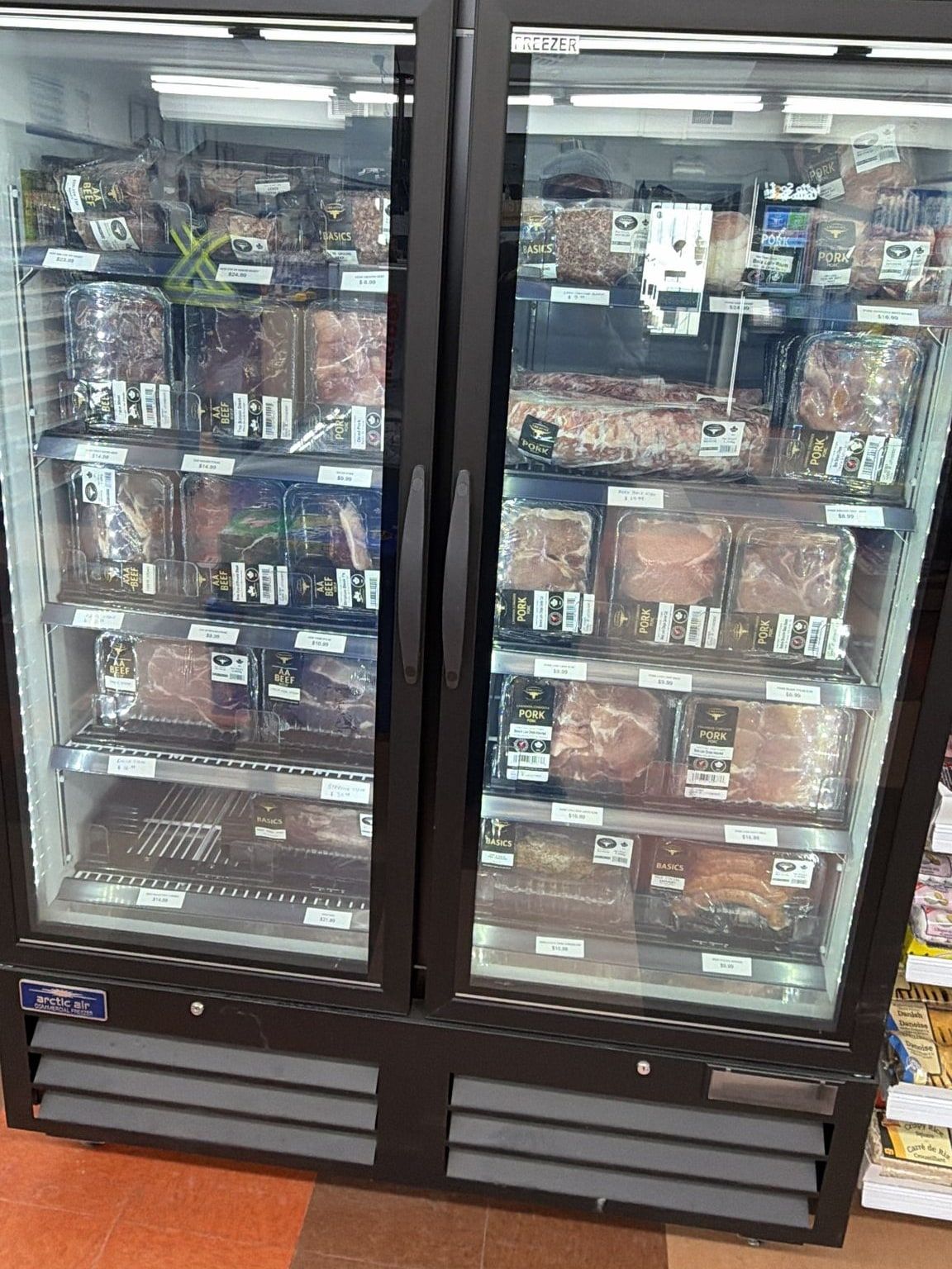 The meat freezer in the middle of the store, stocked with packaged beef and pork
