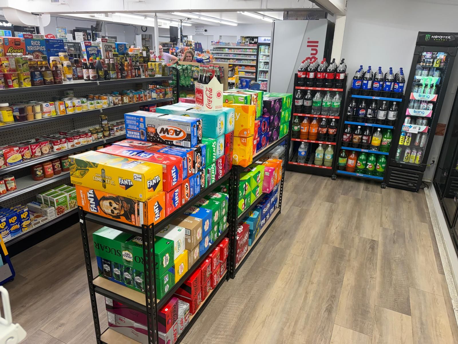 Cases of pop and water stacked in front of the grocery shelves at Garven Convenience