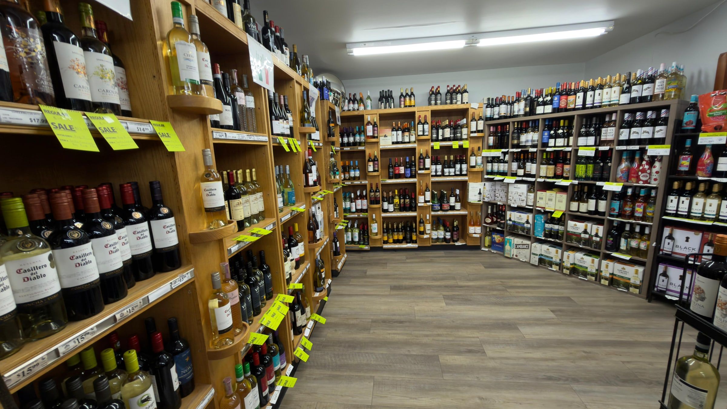 The wine aisle on wooden racks, with sale tags along the shelf edges